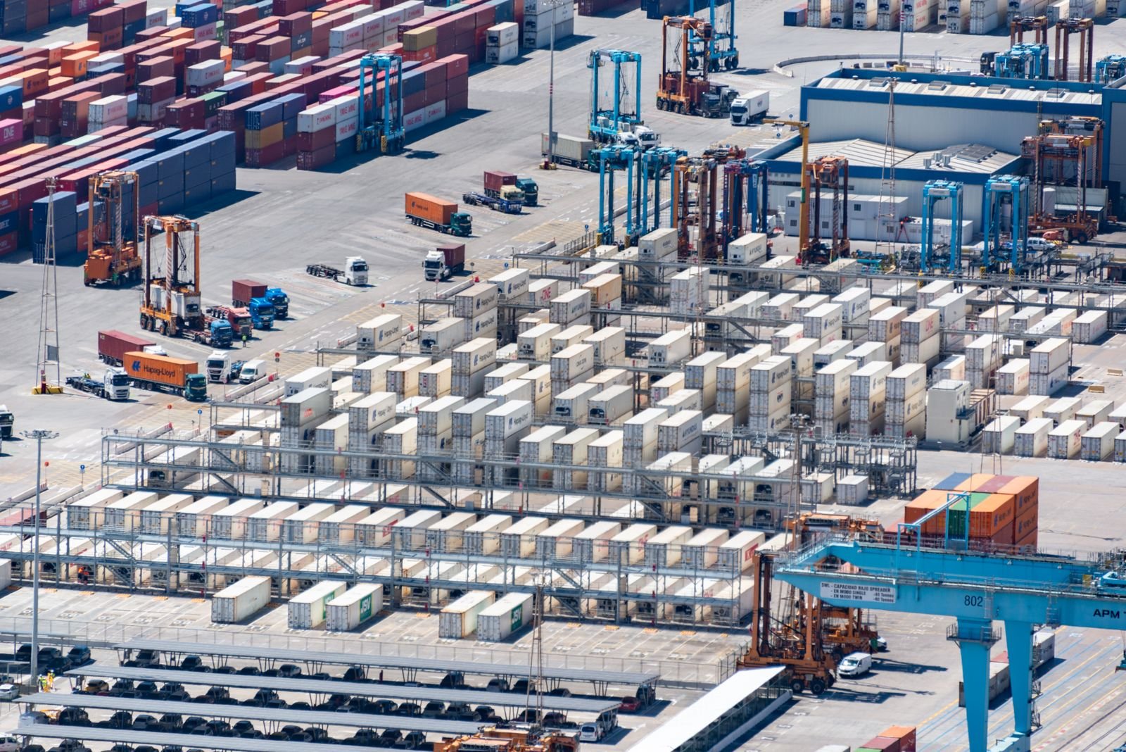 An aerial image showcasing a bustling cargo port with stacked containers and logistics machinery