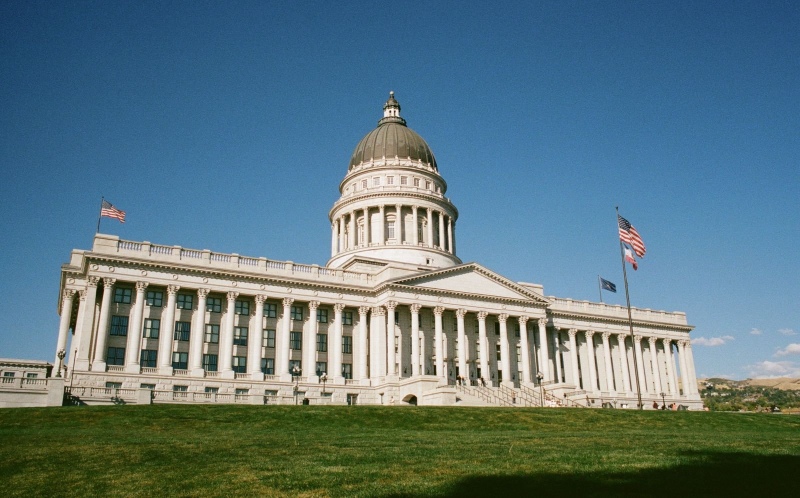 A grand architectural government structure under a clear blue sky with flags waving