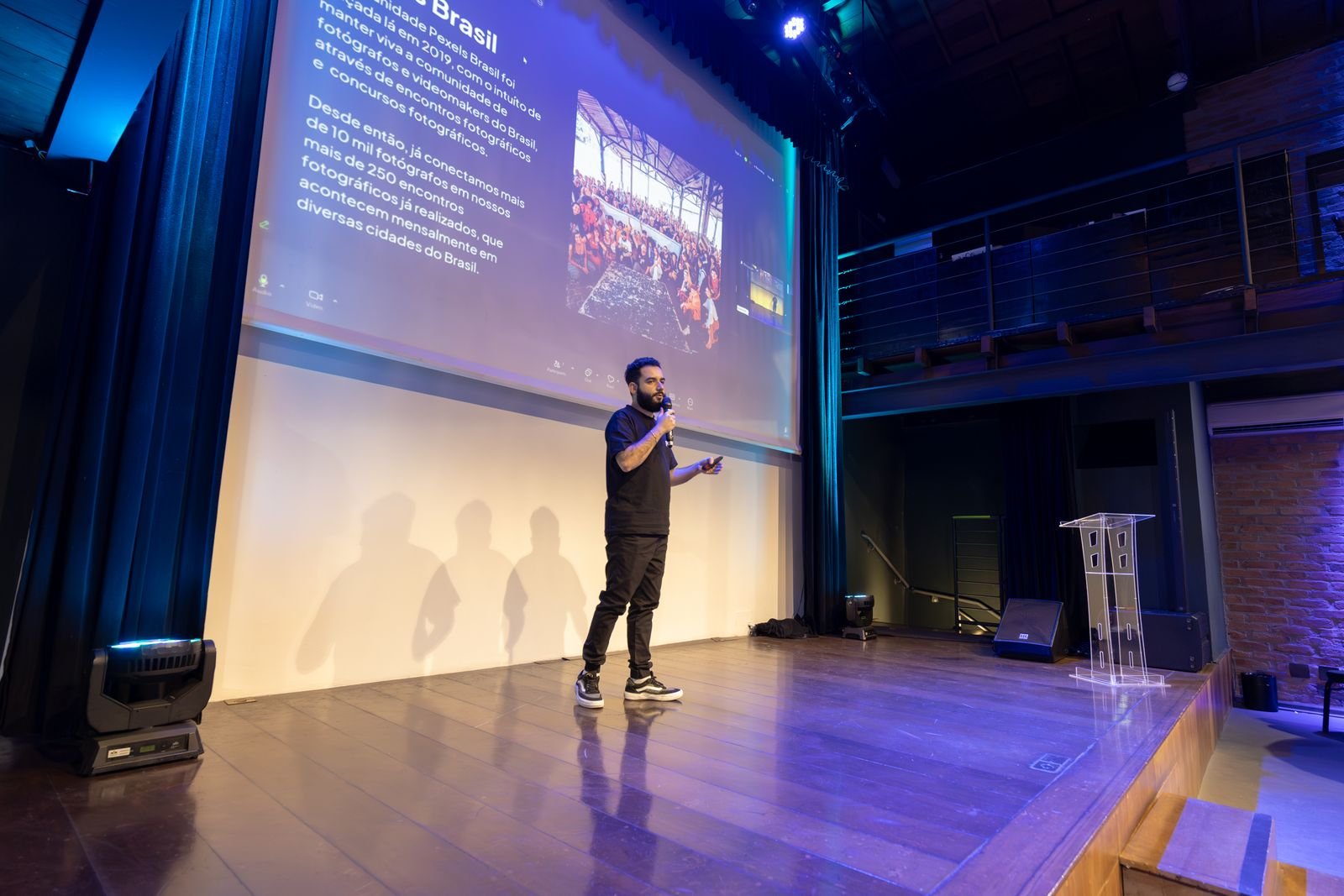 Speaker presenting at a conference with a projected presentation slide on screen