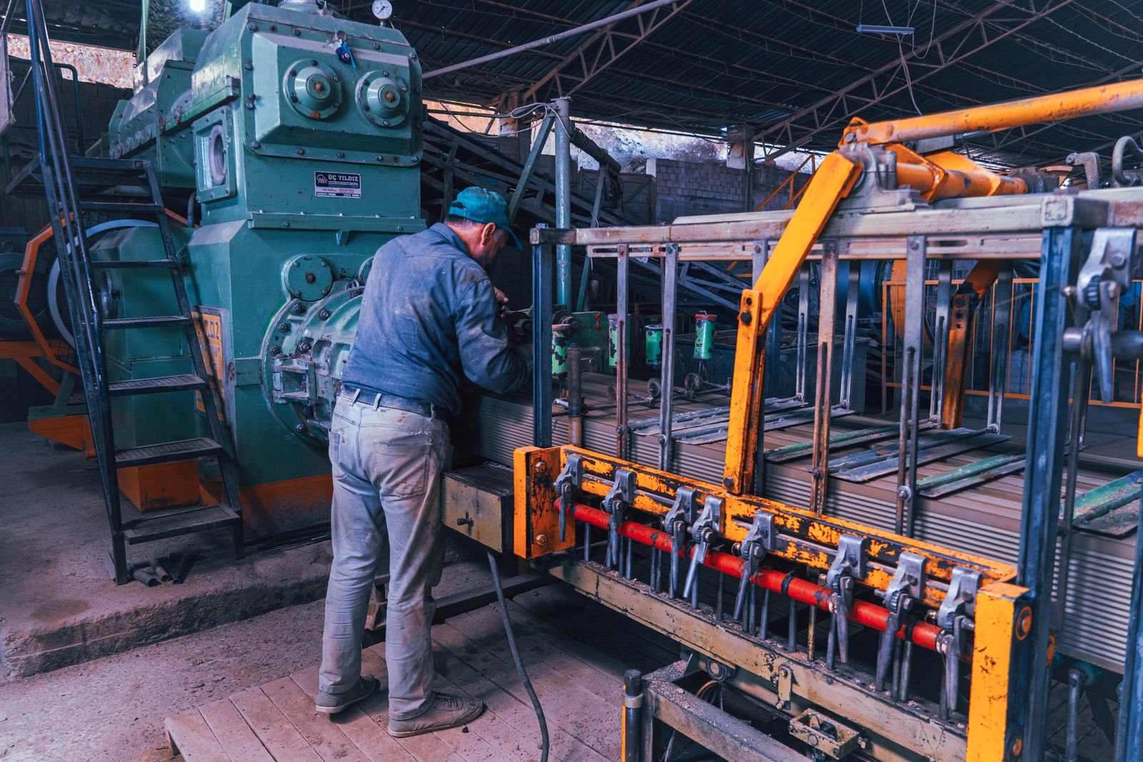 A factory worker operates heavy machinery in an industrial setting, depicting a typical manufacturing scene