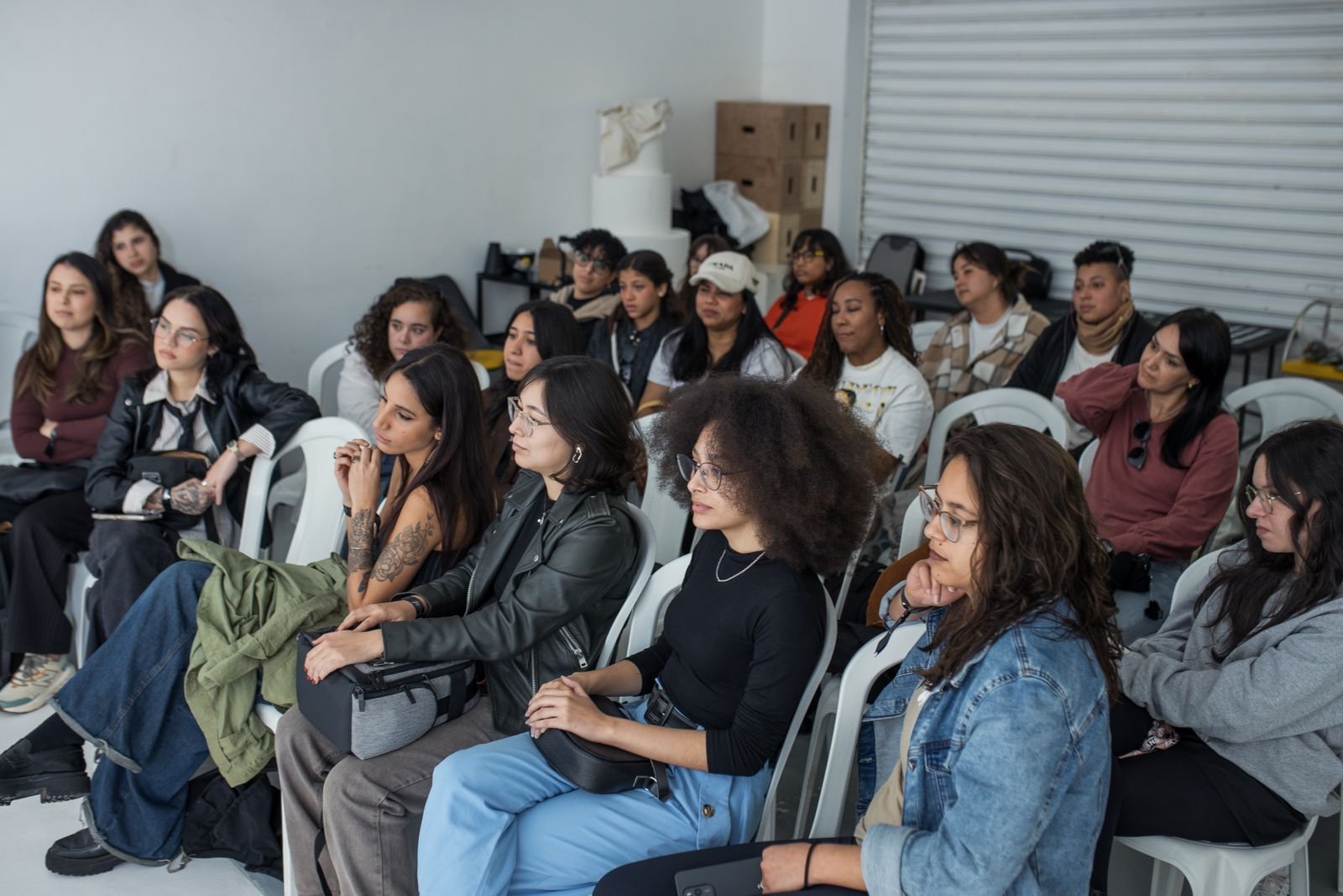 A diverse group of adults attentively listening during an indoor workshop session