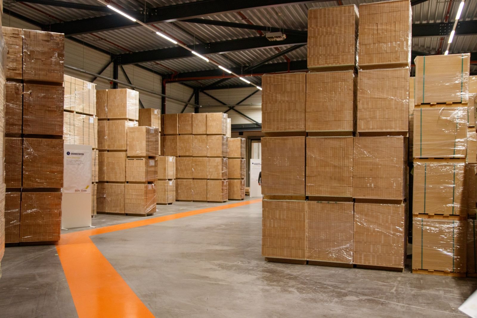 A spacious industrial warehouse filled with stacked cardboard boxes for storage and shipping