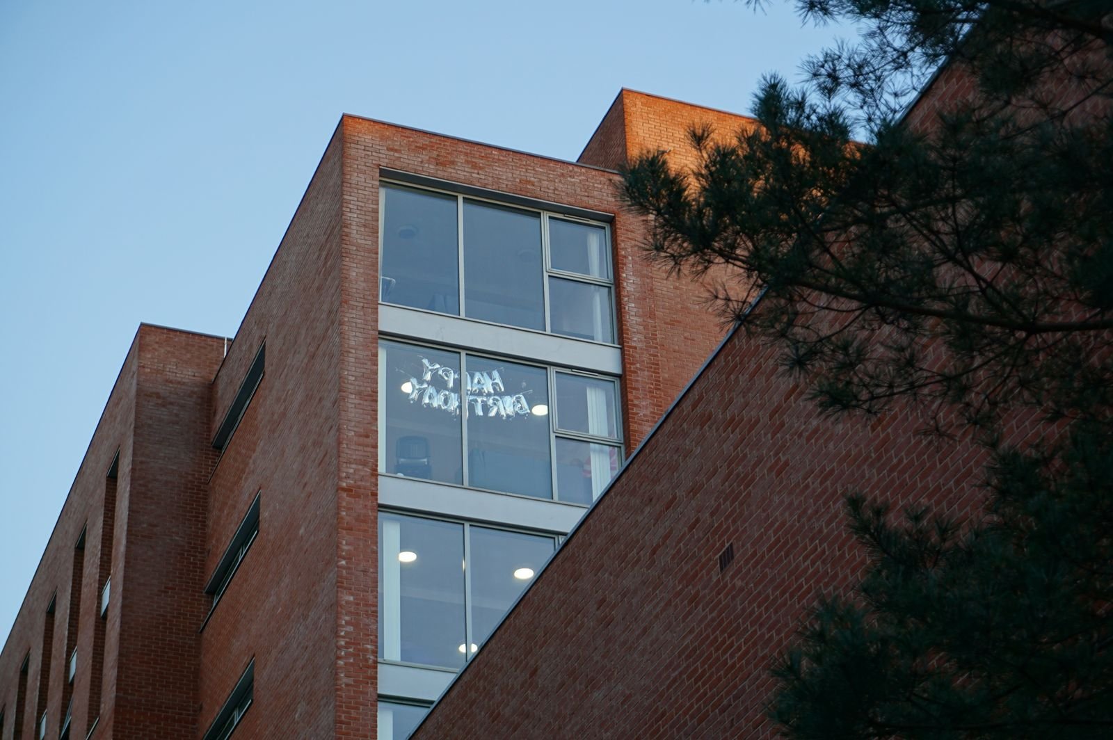 Low-angle view of a modern university building with brick facade and large glass windows