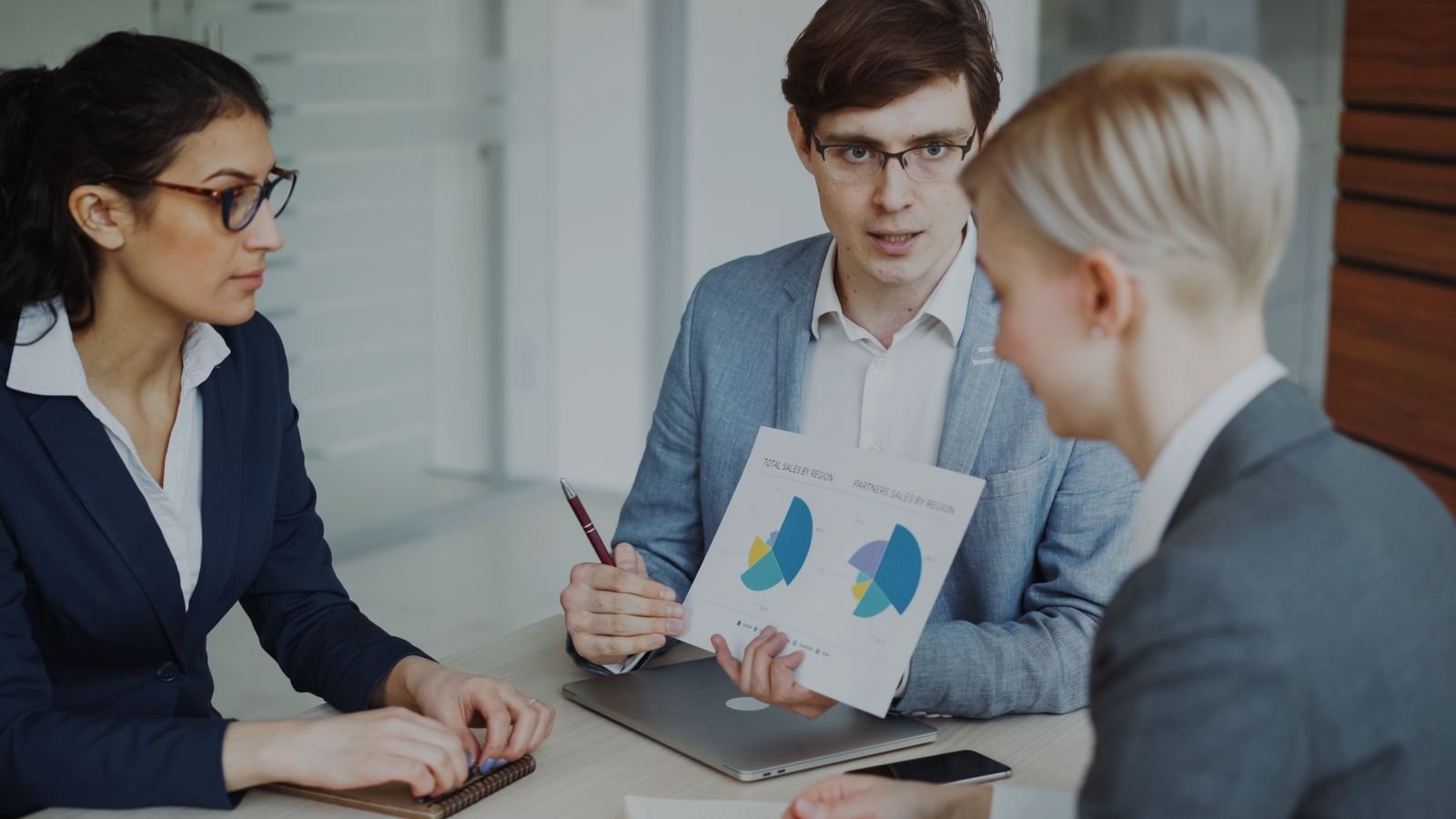 Team of professionals discussing sales strategies with charts in a modern office
