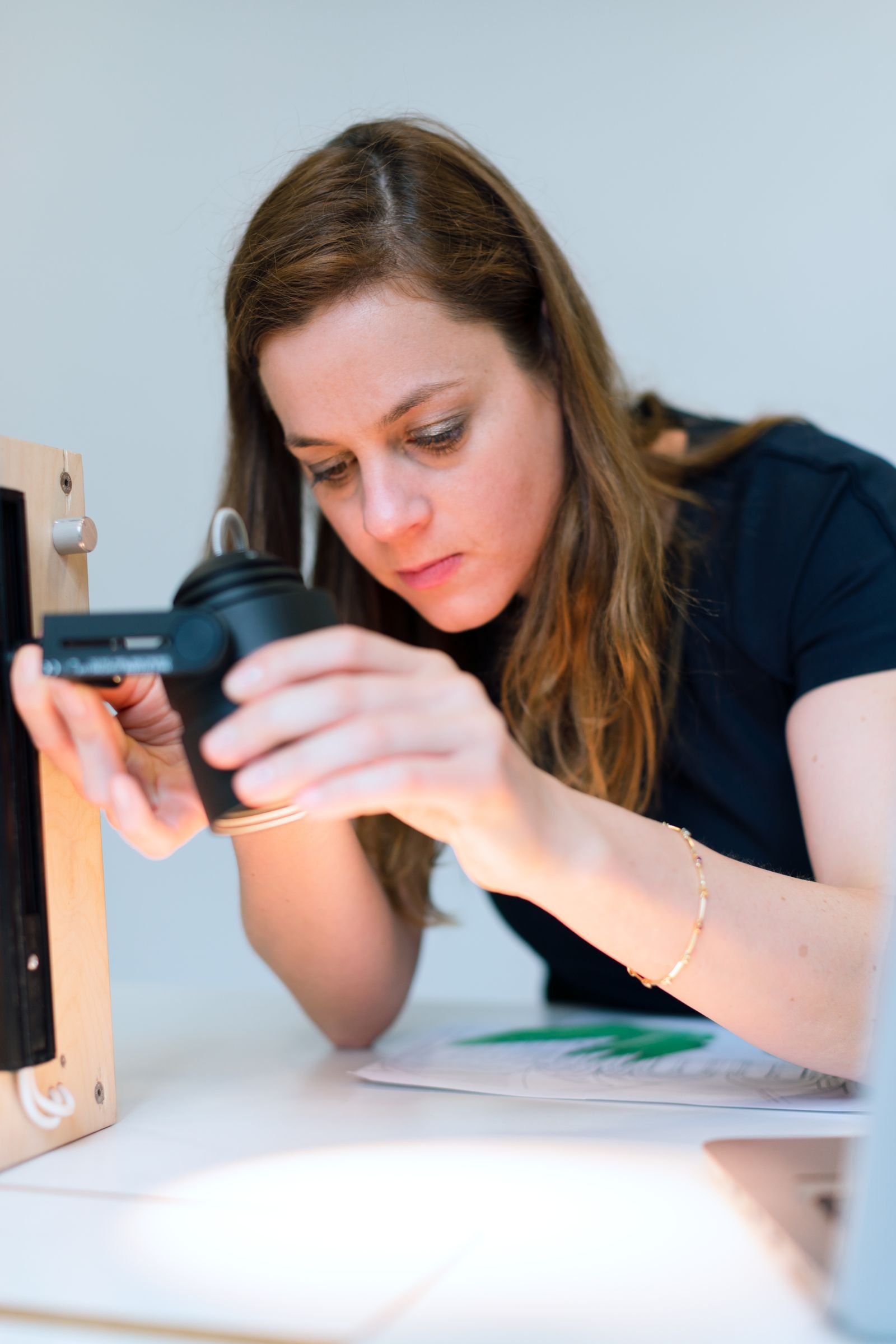 A focused female engineer tests a prototype light fixture in a modern office setting, highlighting engineering and design work