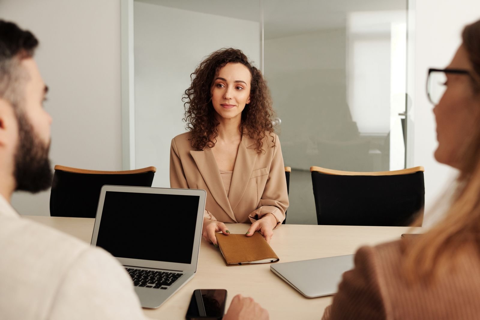 A woman in a business suit participates in a job interview, showcasing professionalism and modern office environment