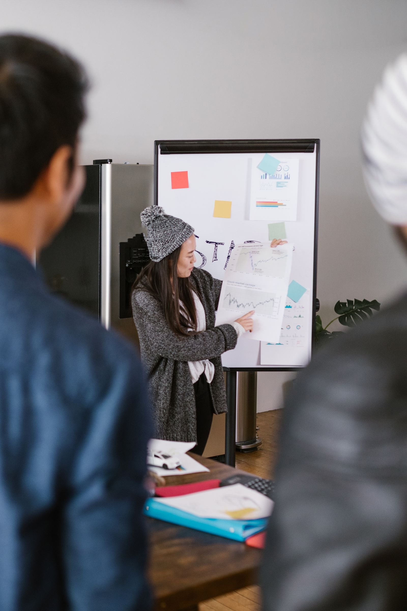 A young woman presenting business plans to a team in a modern office setting