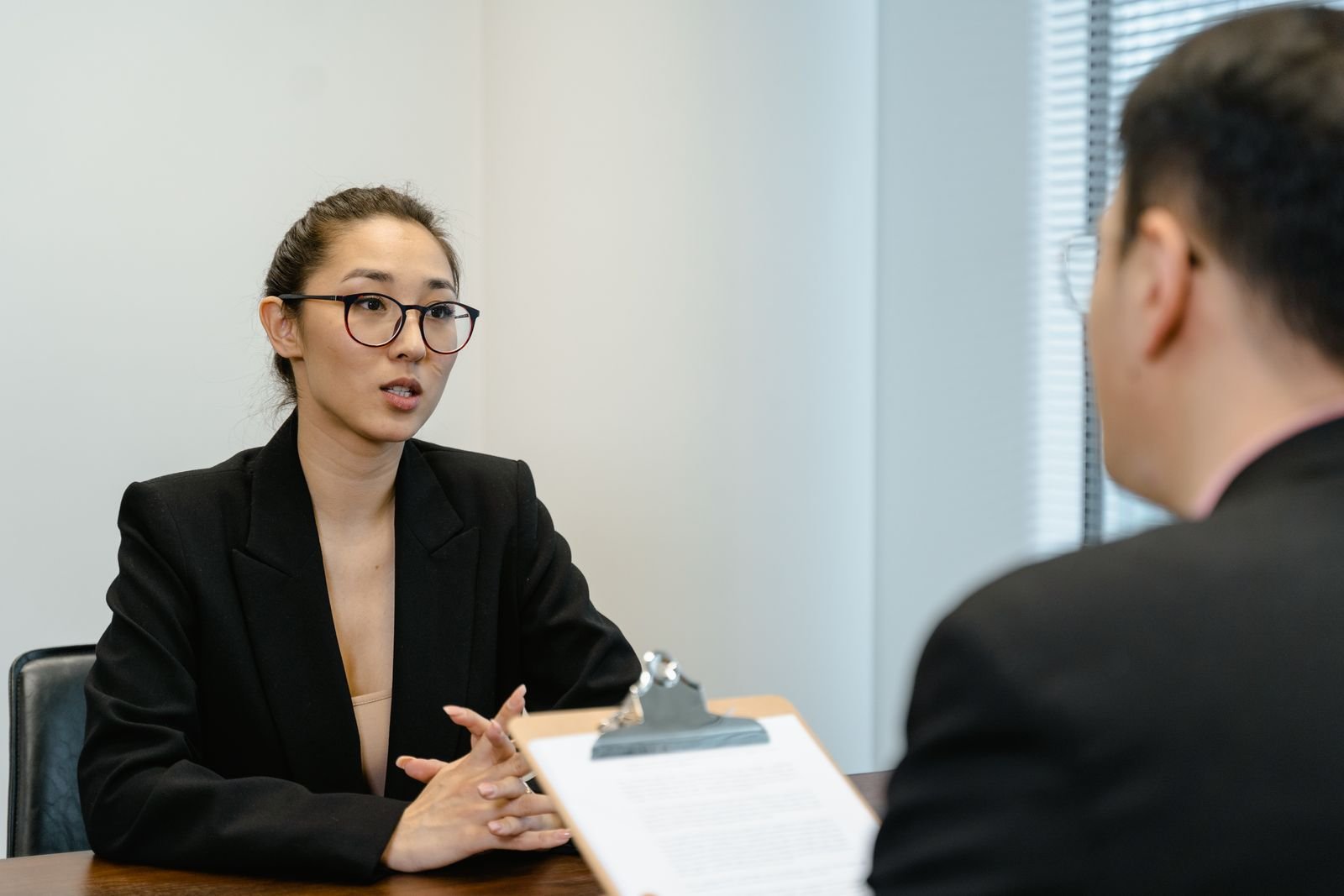 A focused interview scene in an office environment with business attire and a clipboard