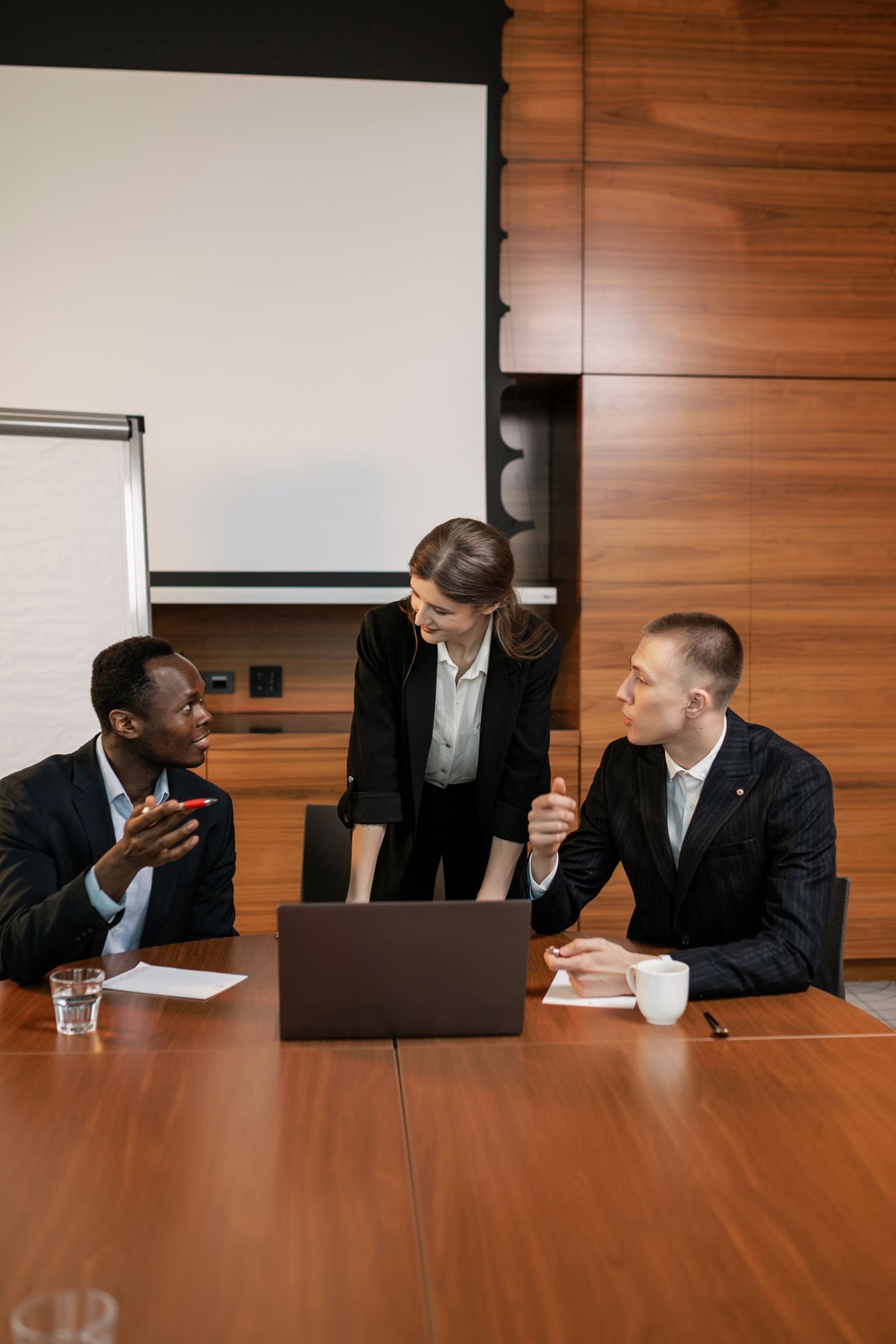 Professional team discussing around a laptop in a modern conference room