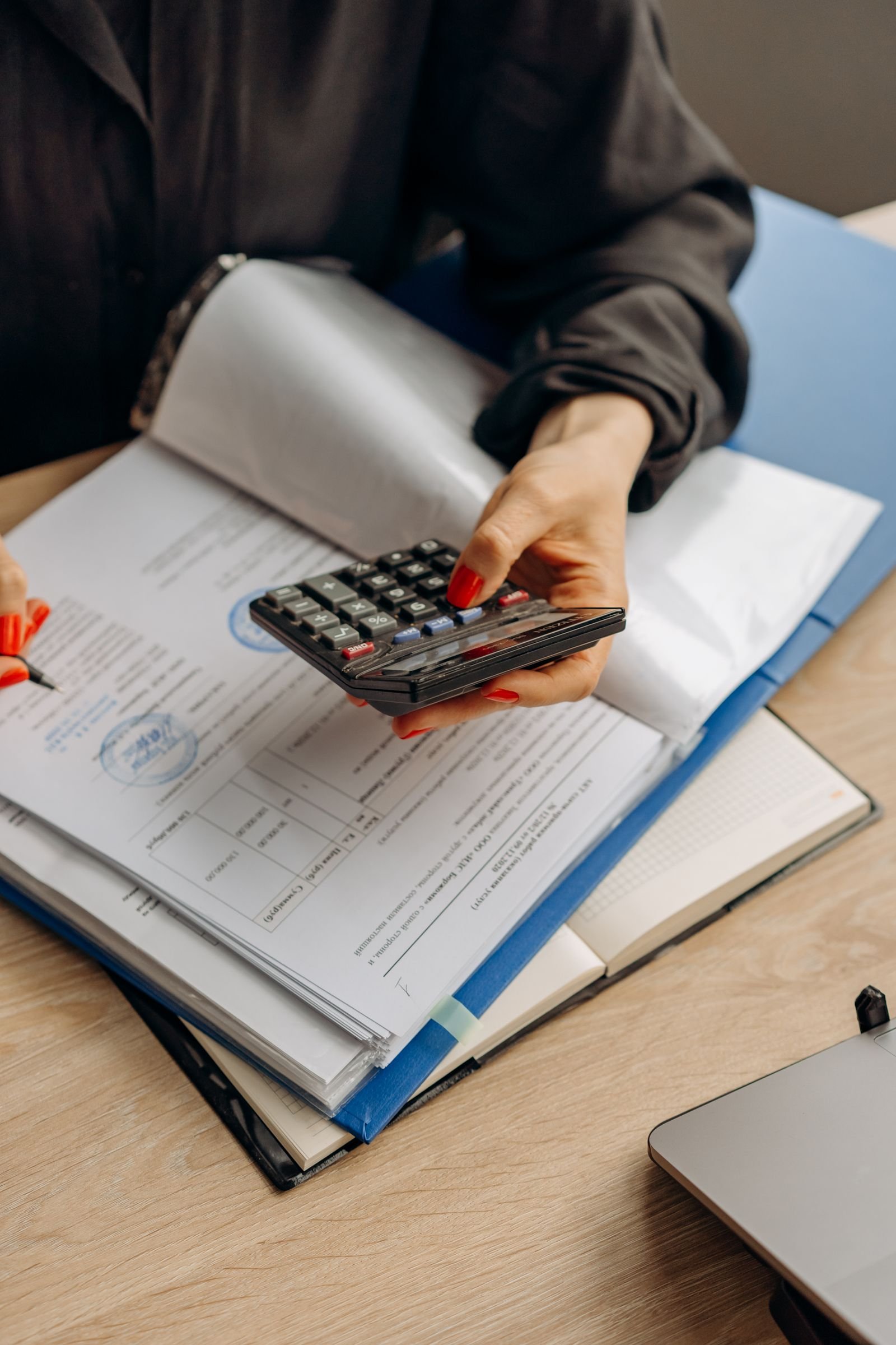 Person using calculator and documents for accounting tasks in an office setting
