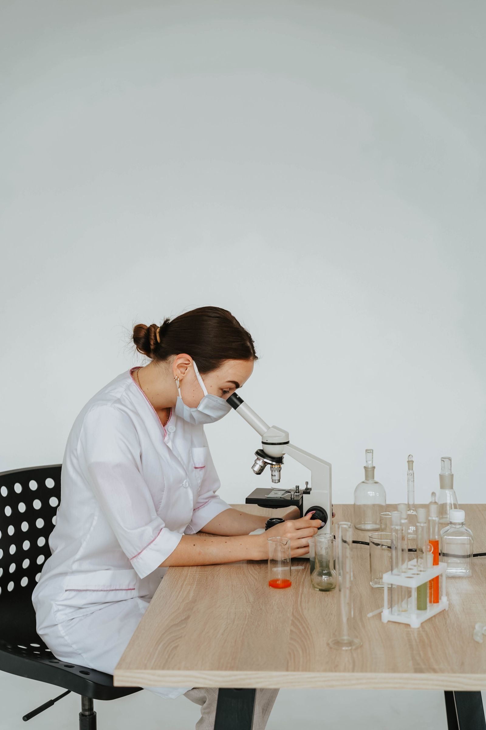 A female scientist conducting experiments in a laboratory using a microscope and glassware