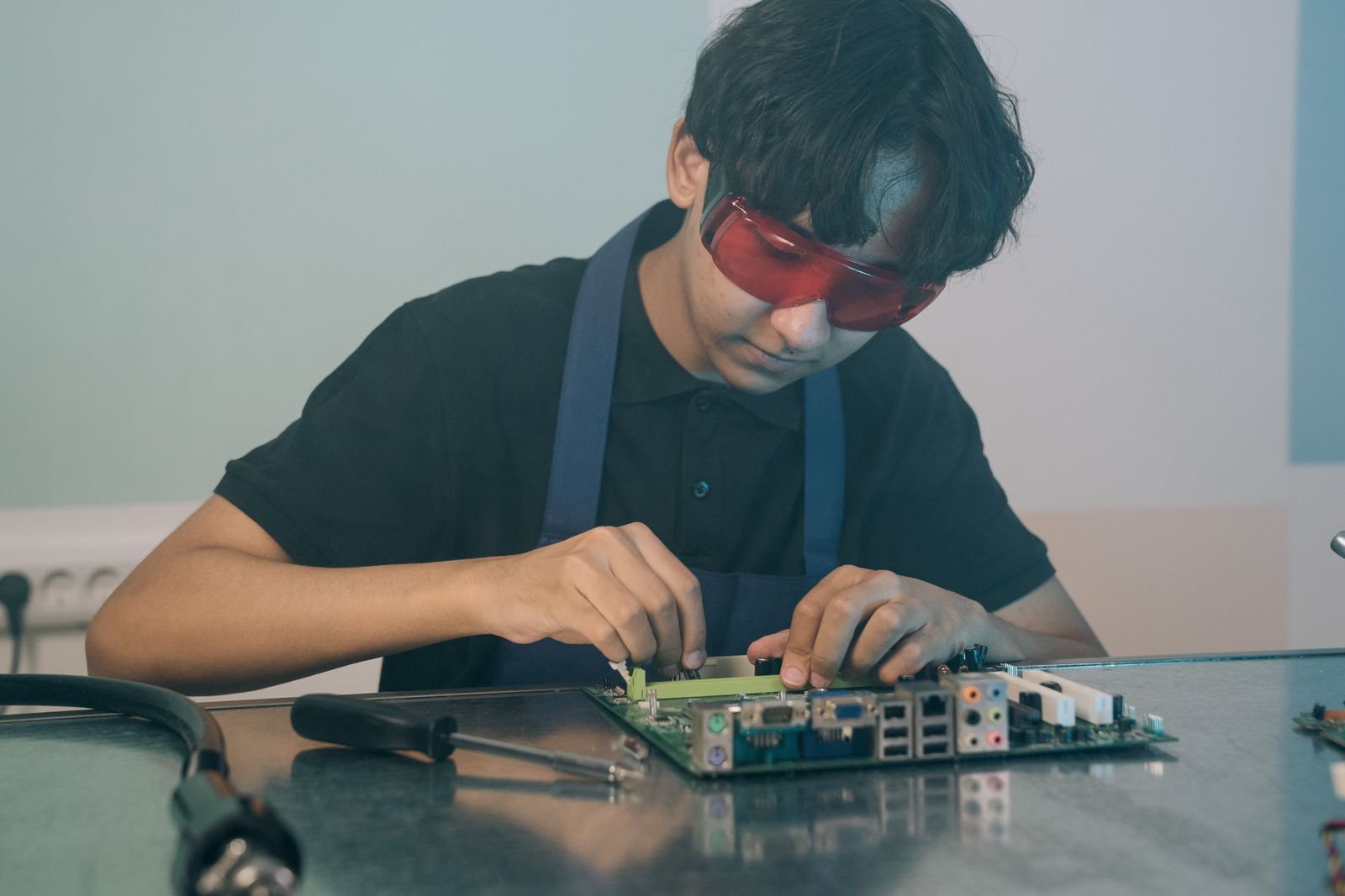 Young technician working with precision on a circuit board, demonstrating focused attention and technical skill indoors