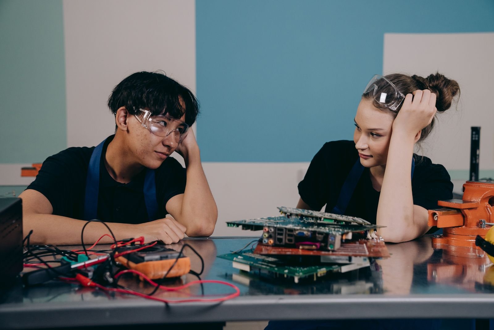 Two young engineers at a workbench, collaborating on electronics with circuit boards