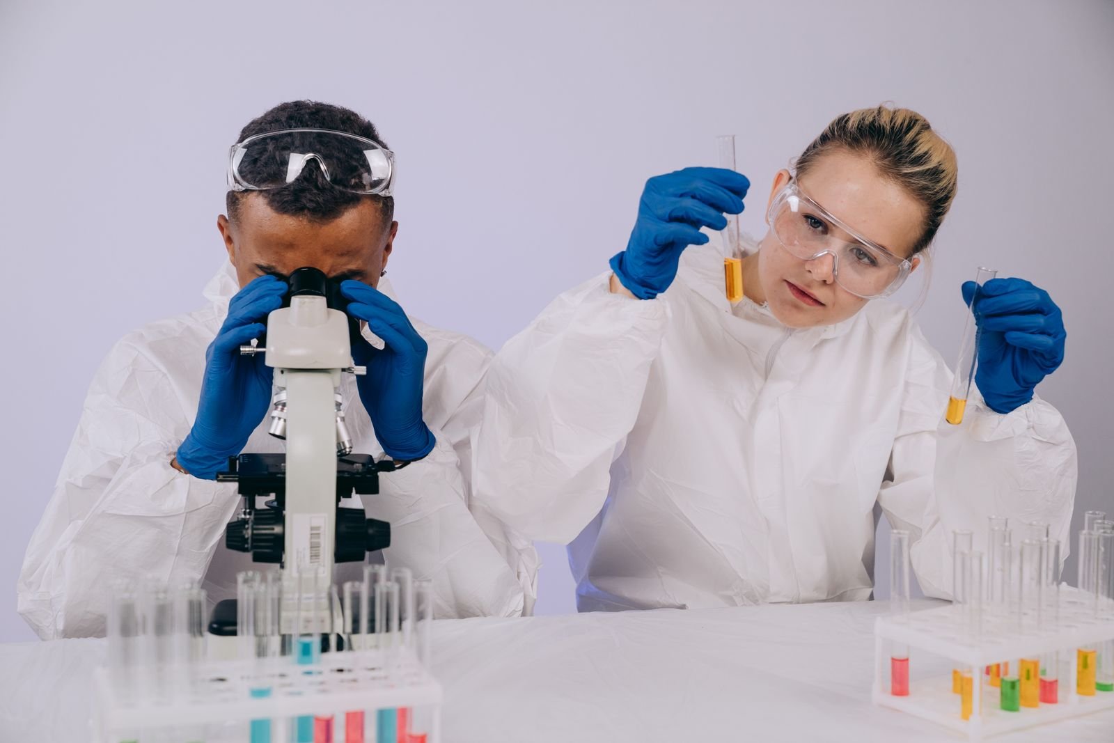 Two scientists in lab coats conduct research with a microscope and test tubes in a laboratory